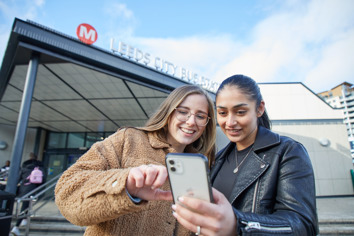Two women looking at a phone buying a ticket